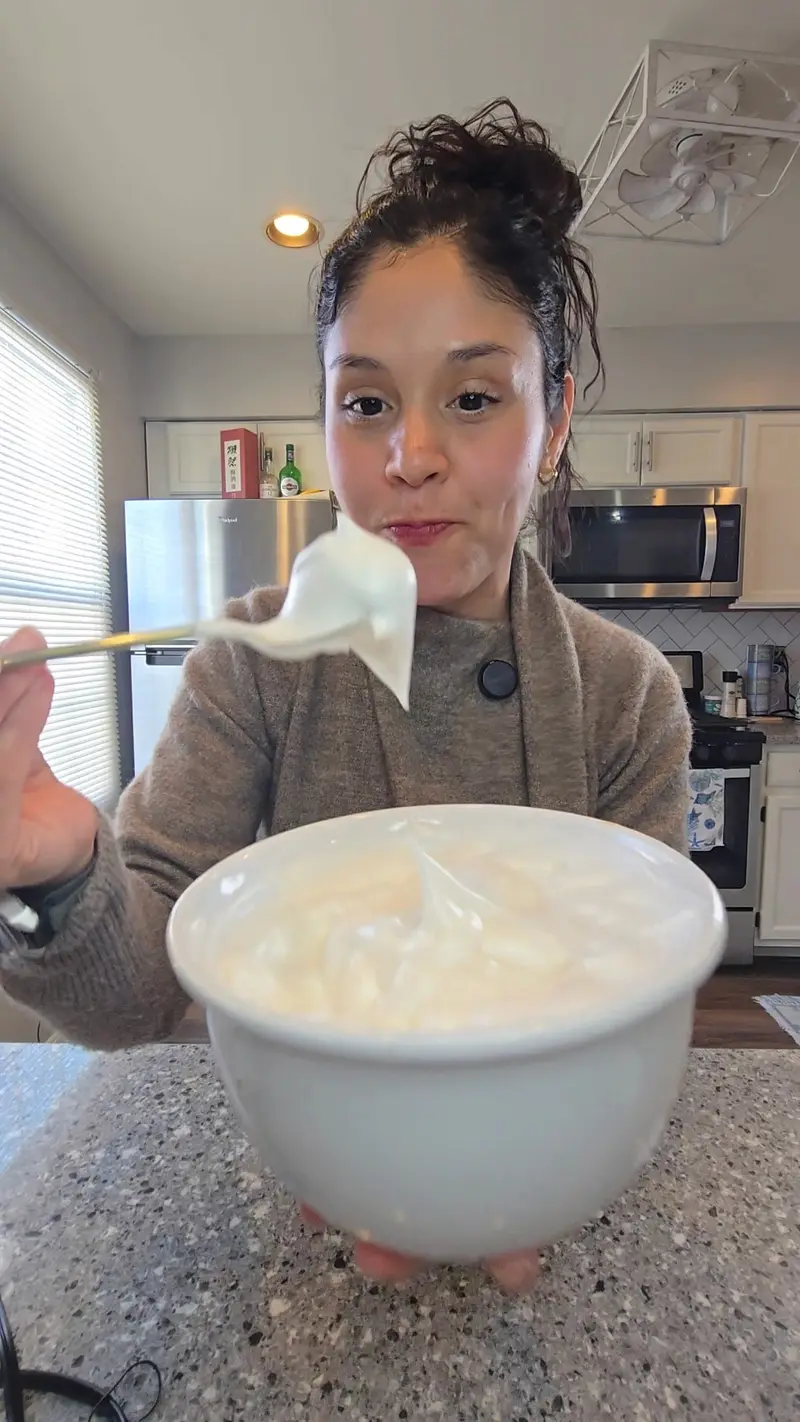 Crystal lifting a spoonful of whipped aquafaba to show it holding stiff peaks