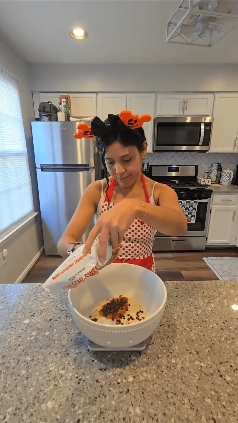 Crystal pouring gluten-free flour into a bowl of pumpkin and chocolate chips