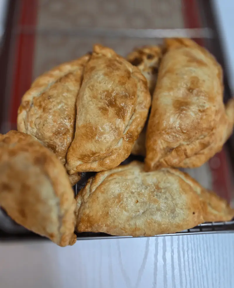 Golden baked guava and cheese empanadas cooling on a wire rack