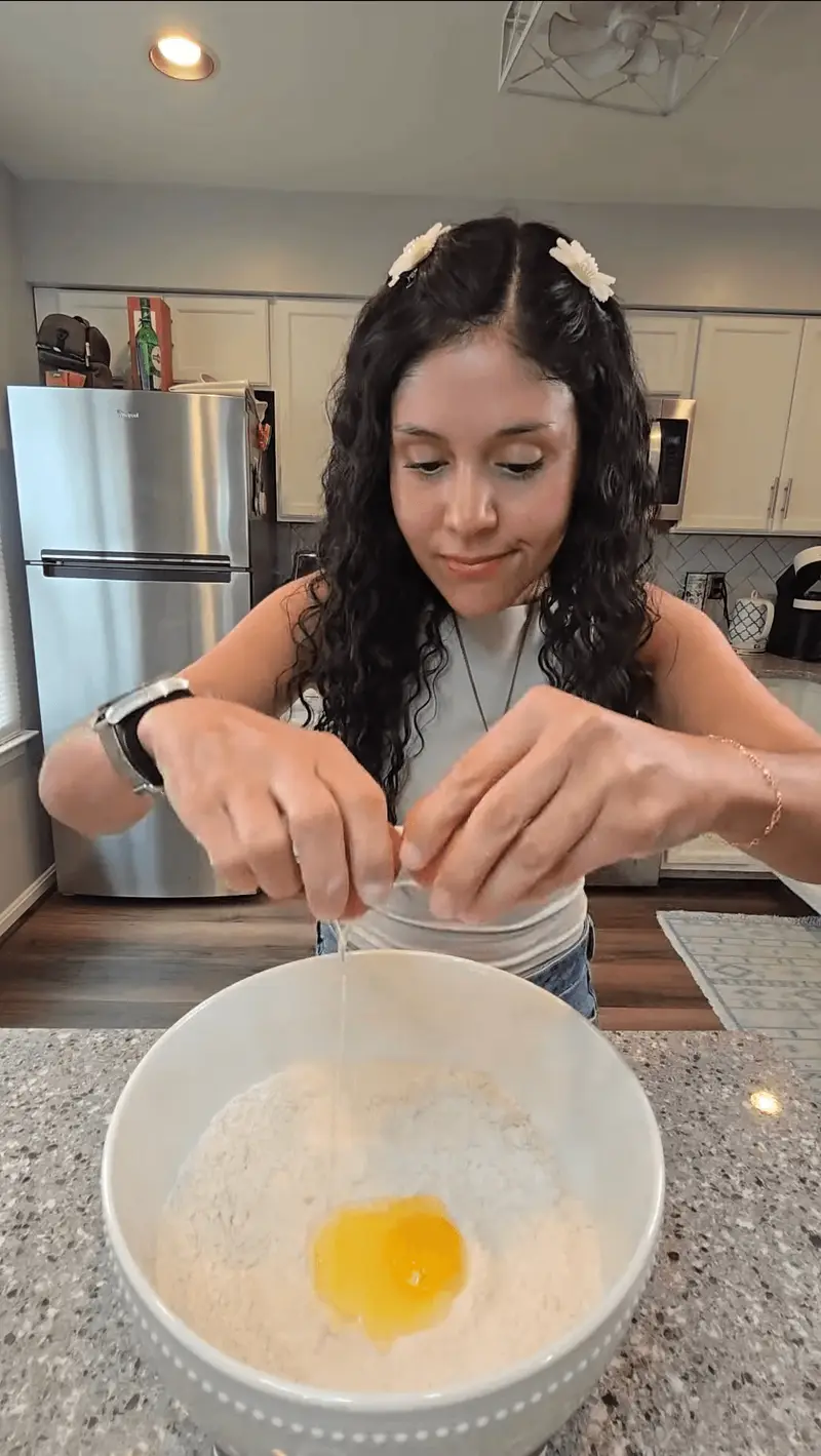 Crystal cracking an egg into the flour mixture