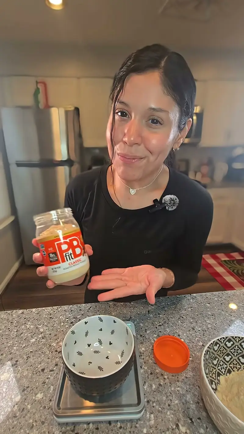 Crystal holding up a jar of peanut butter beside her mixing bowls
