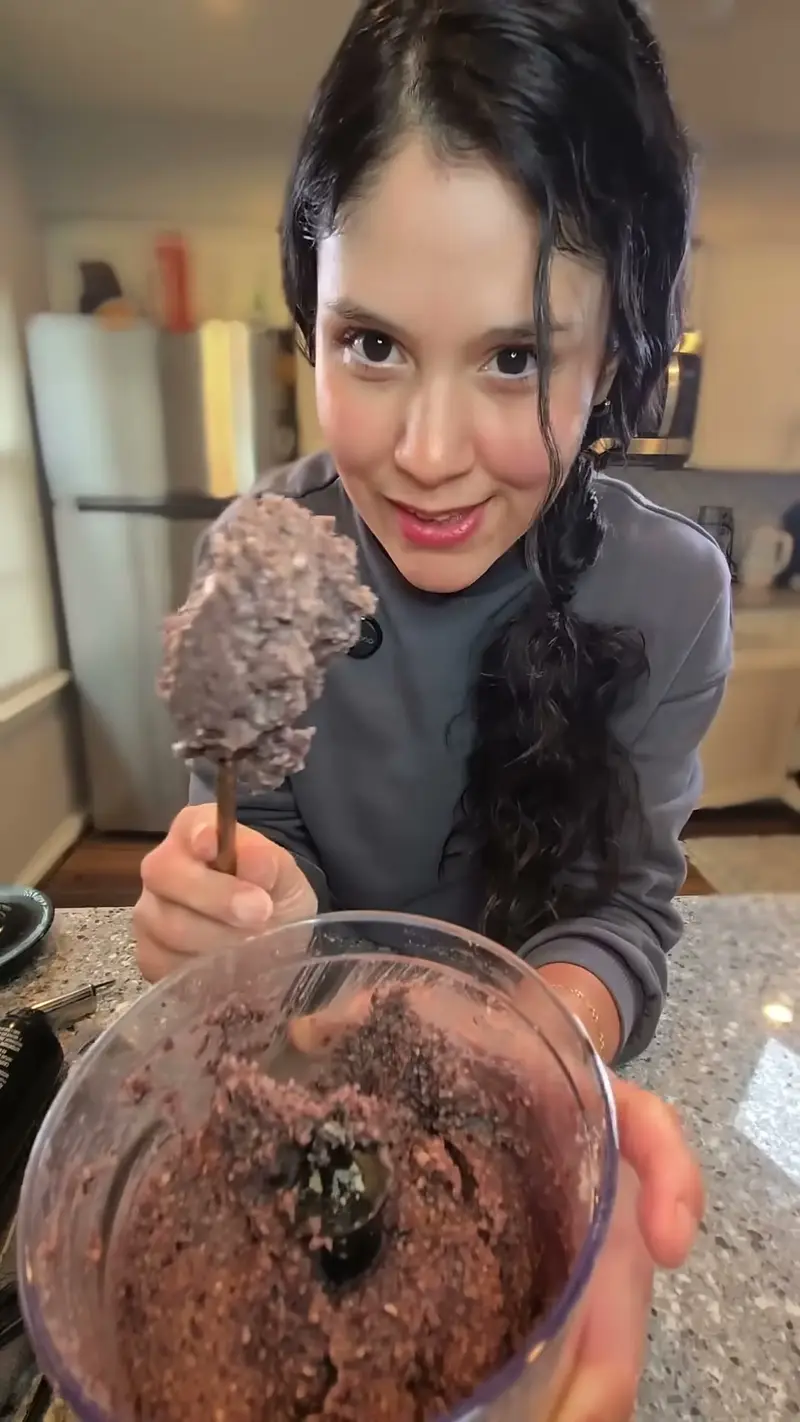 Crystal holding up a spoonful of the blended black bean patty mixture