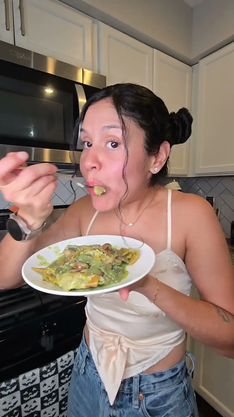 Crystal eating a plate of pesto mushroom pasta at the counter