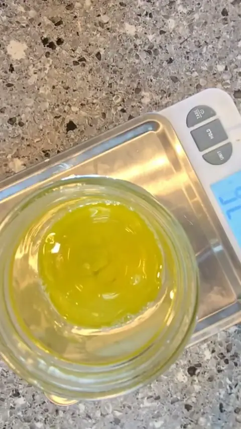 A jar of olive oil dressing sitting on the kitchen scale