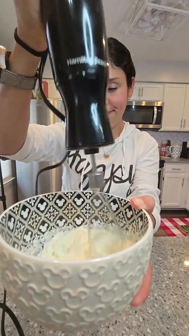 Crystal whipping the cream topping with a hand mixer in a patterned bowl