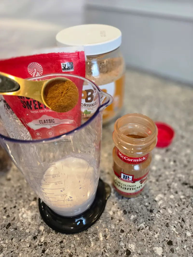 Crystal adding cinnamon to the measuring jug of coconut milk