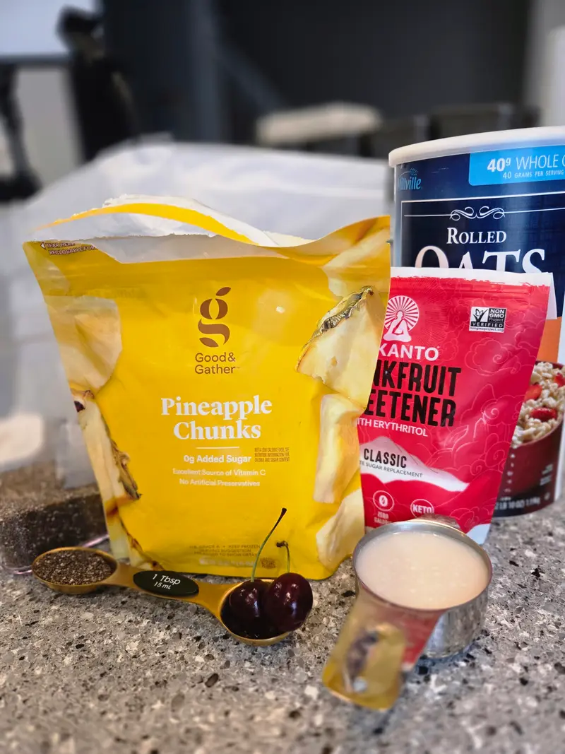 The ingredients on the counter: pineapple chunks, rolled oats, monkfruit sweetener and a cherry