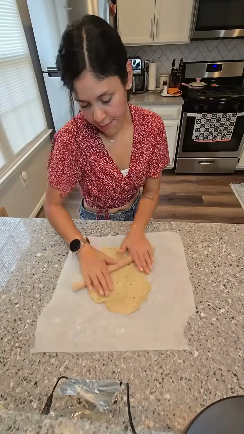 Crystal rolling out the rosemary cracker dough on parchment paper