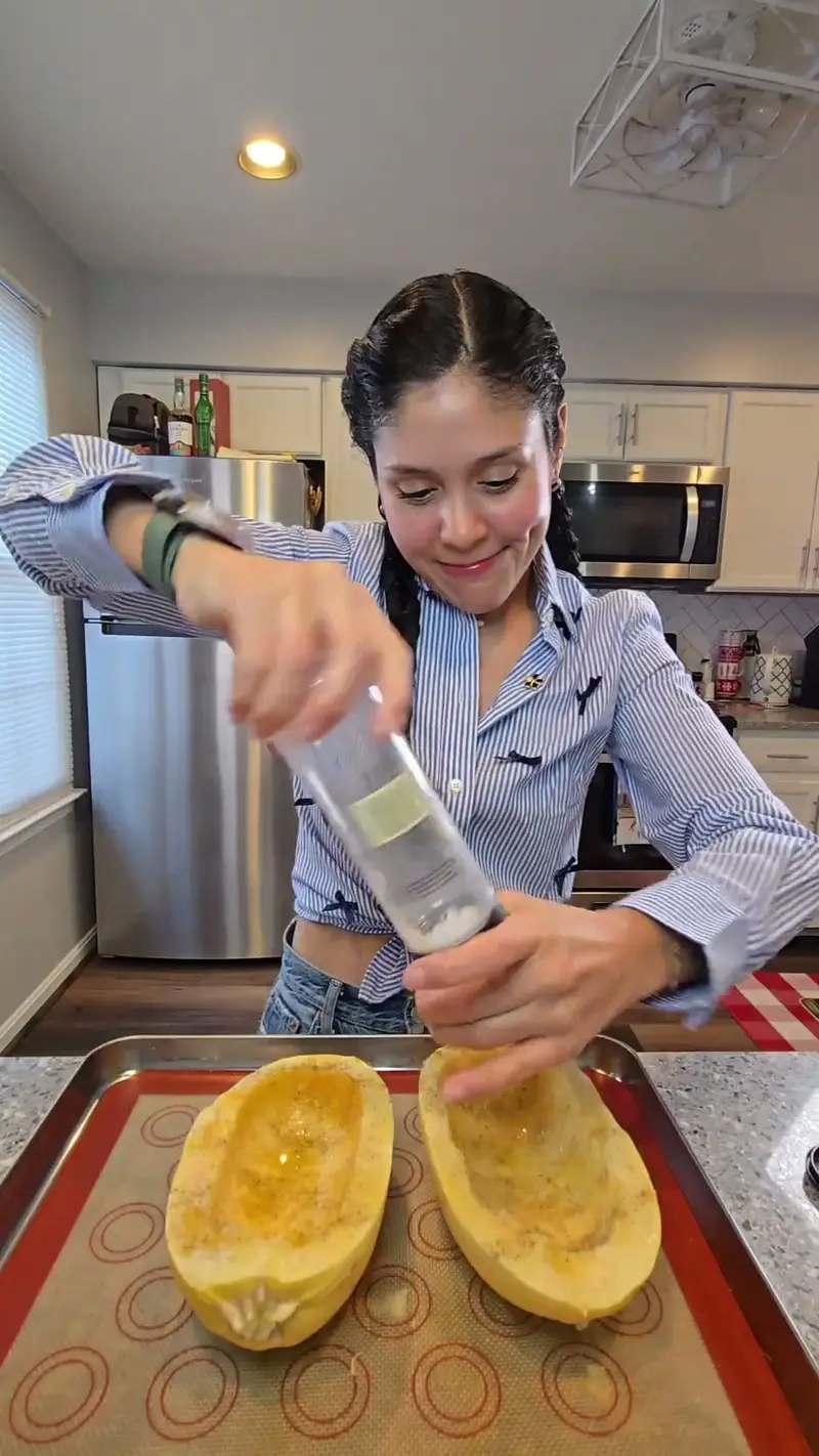 Crystal seasoning the oiled spaghetti squash halves before roasting