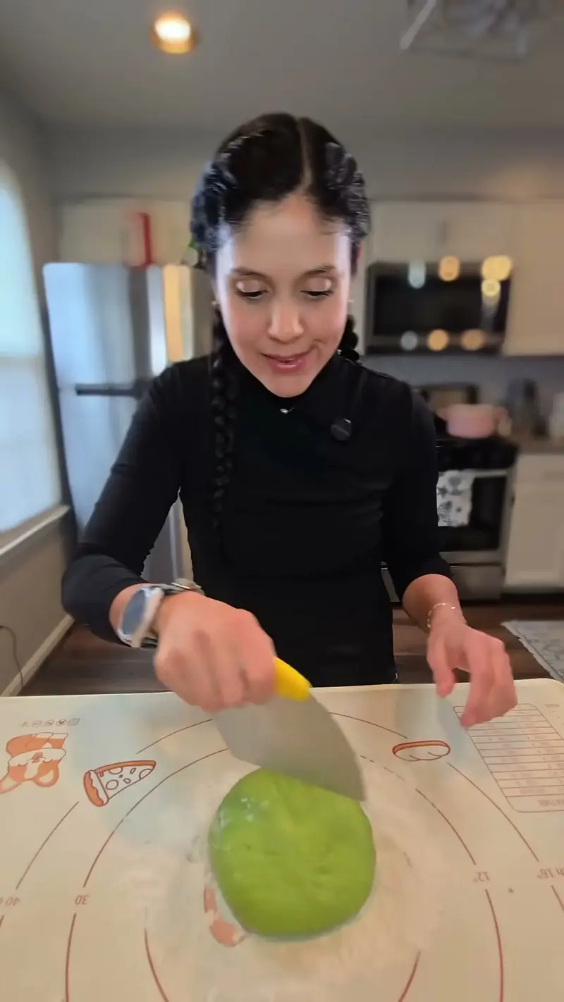 Crystal cutting the green dough with a bench scraper on the mat