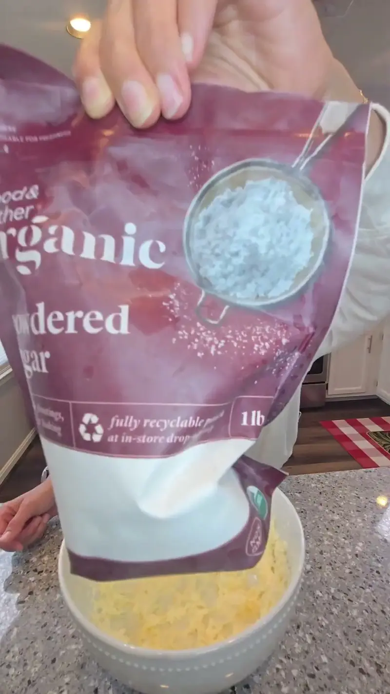 Crystal scooping powdered sugar from the bag into a bowl of butter
