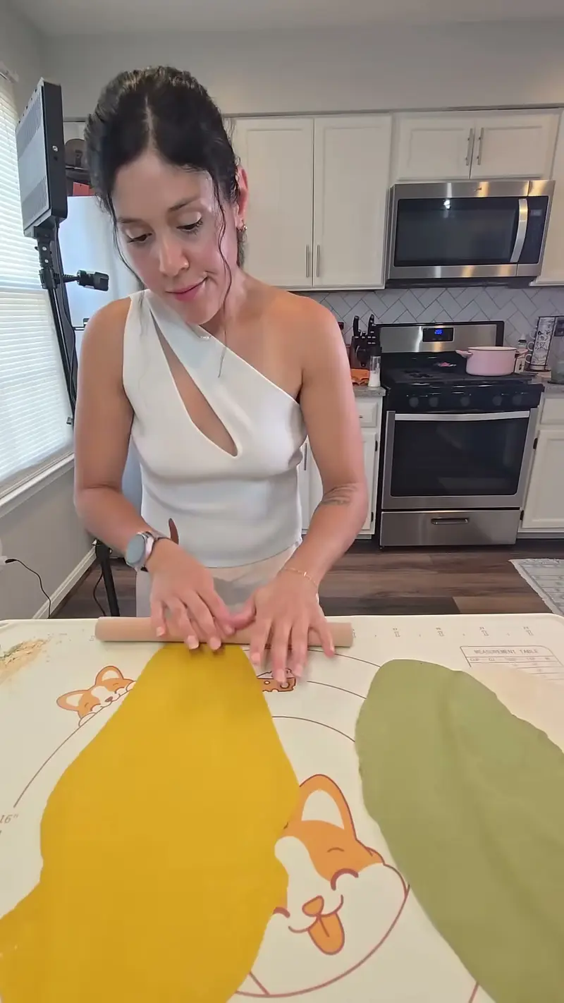 Crystal rolling out the yellow dough beside a sheet of green dough
