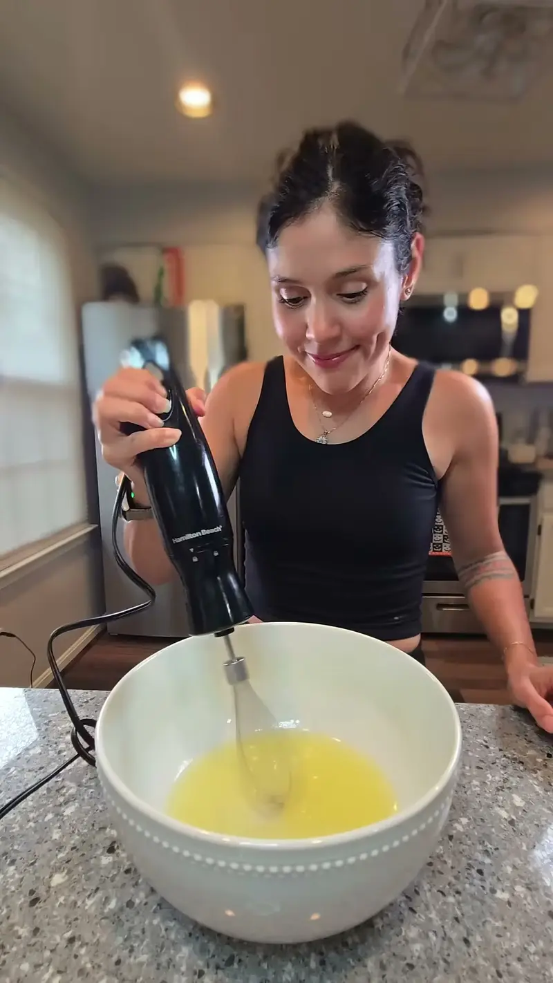 Crystal whisking liquid egg whites in a bowl with an immersion blender